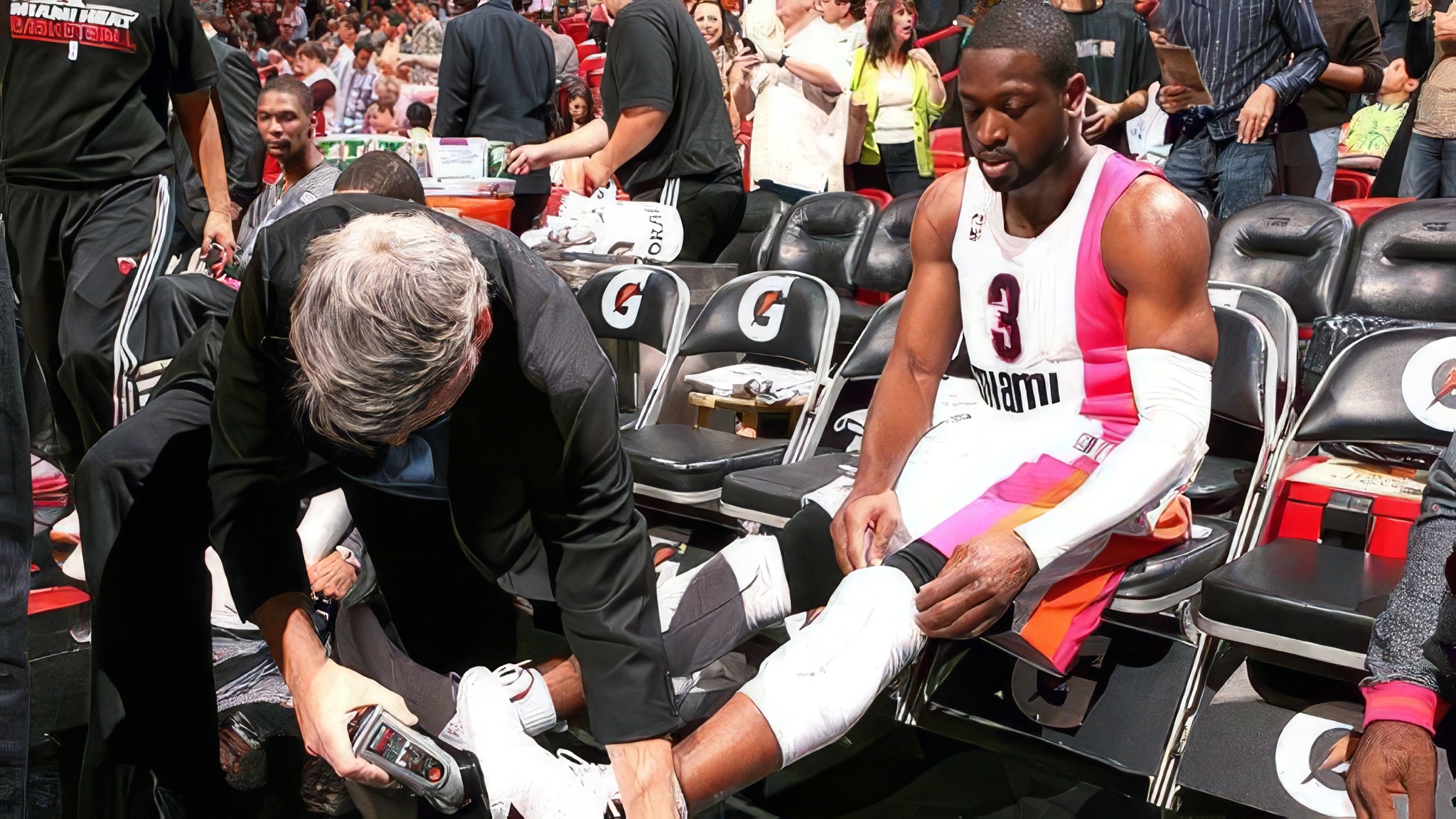 Dwyane Wade courtside before a Heat game while a trainer applies Court Grip to his shoe